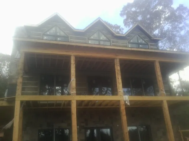 Dormers and porch framing on a large log home under construction — Roof Coating work by our crew in Parkton