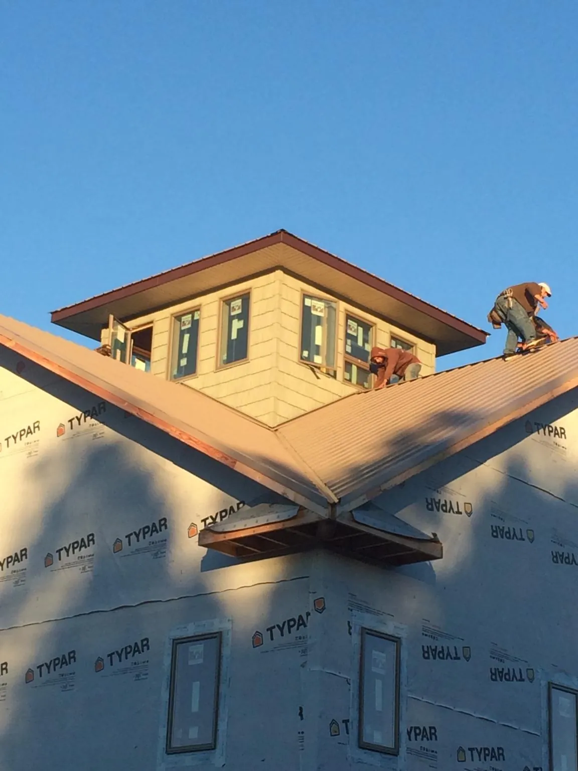 Roofers working around a rooftop cupola on a new metal roof at sunset — Roof Waterproofing in Parkton by Roofing Brothers